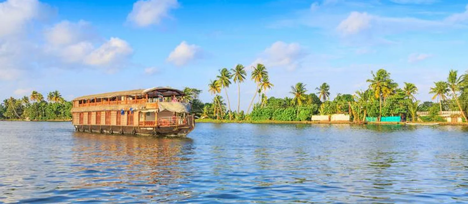 A traditional Kerala houseboat cruising past palm-fringed banks on the Alleppey backwaters