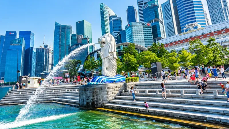 City skyline and waterfront promenade busy with visitors on a bright day